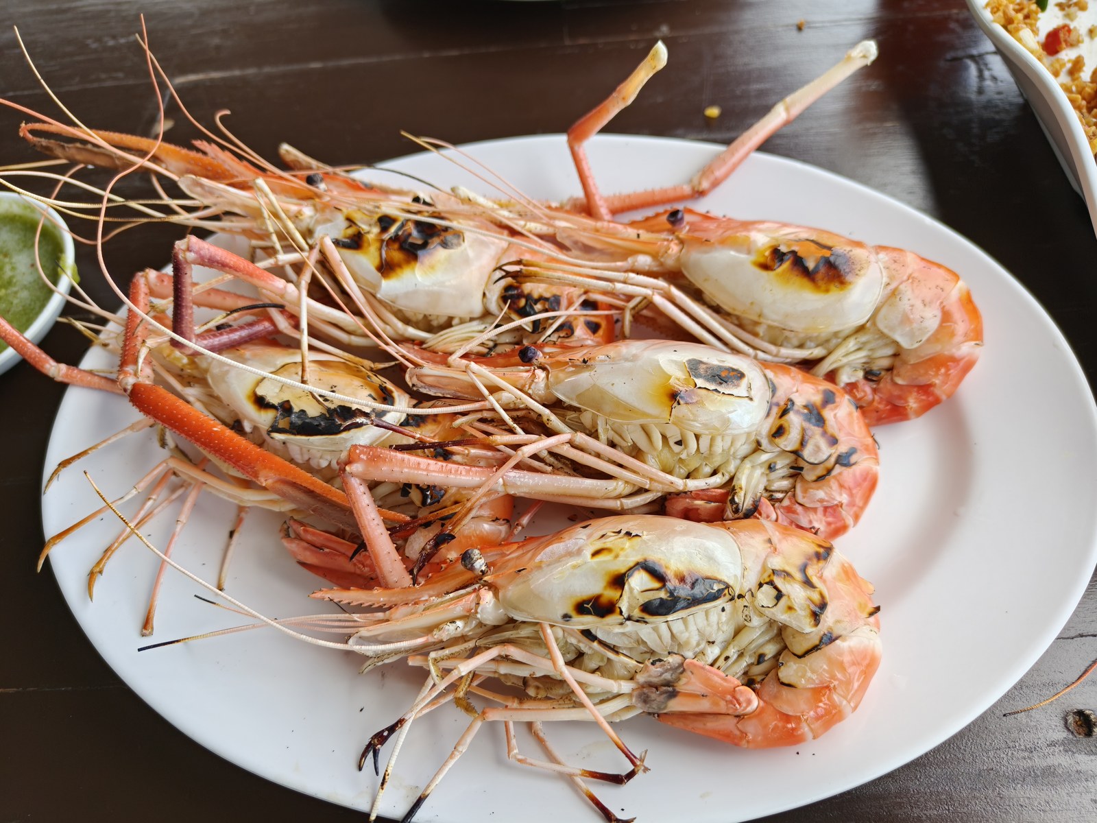 今回注文した焼き海老。焼き目のついた殻付きの海老と緑色のソース。