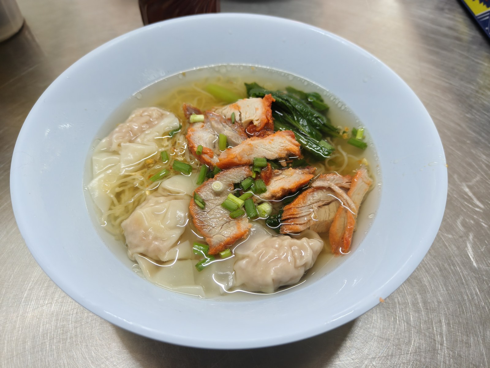 ワンタン状の具と肉、青菜がのった汁麺。提供写真から、注文の選び方を学びます。